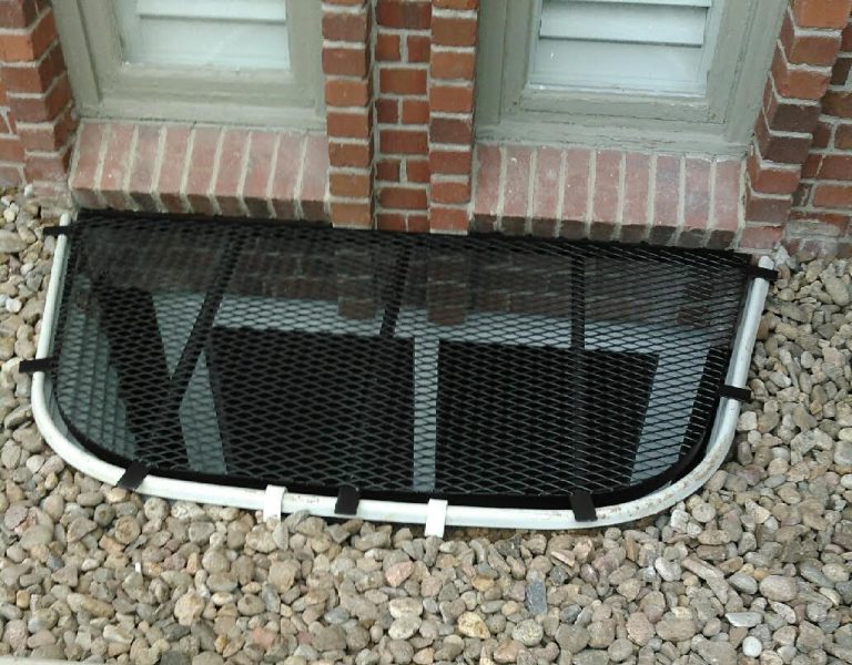 Black mesh grate over a brick-lined window well