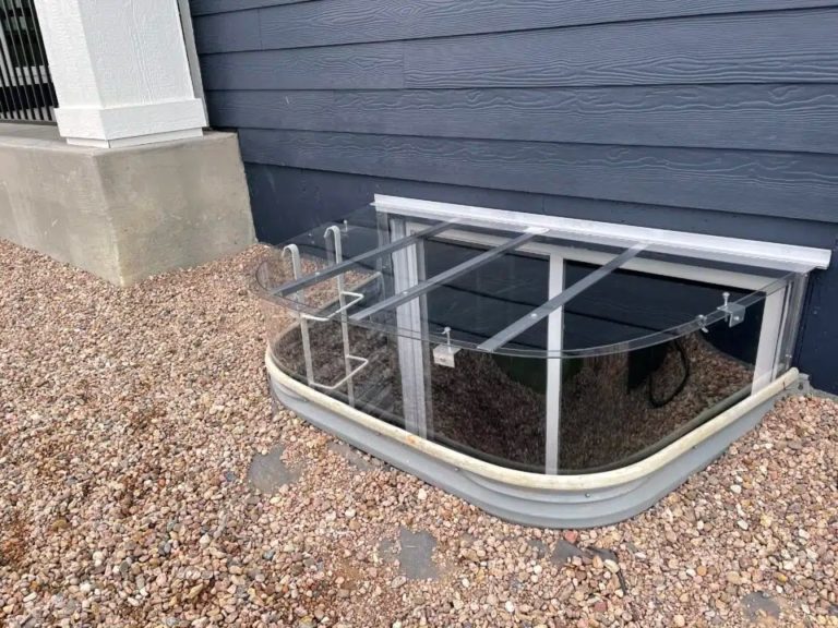 Lean-to window well cover beside a dark gray house