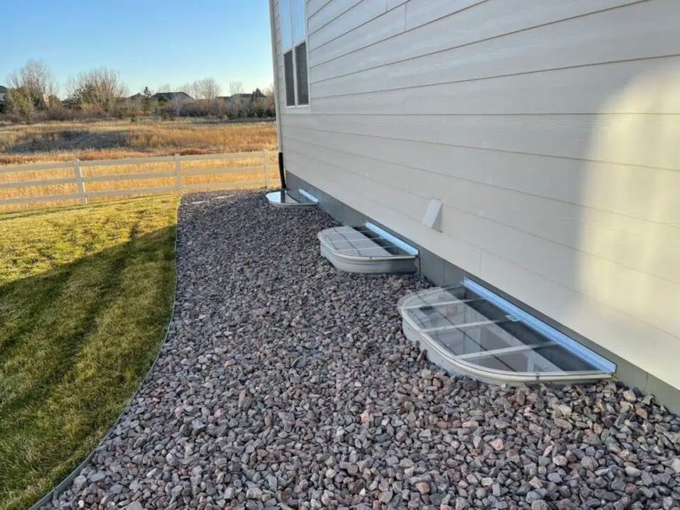 Two clear window well covers along a home's foundation