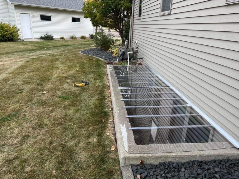 Clear window well cover next to a lawn
