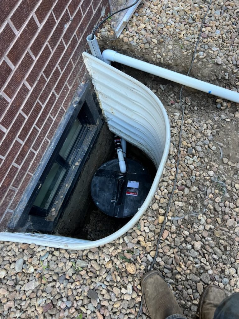 Small sump pump installed at the bottom of a steel window well