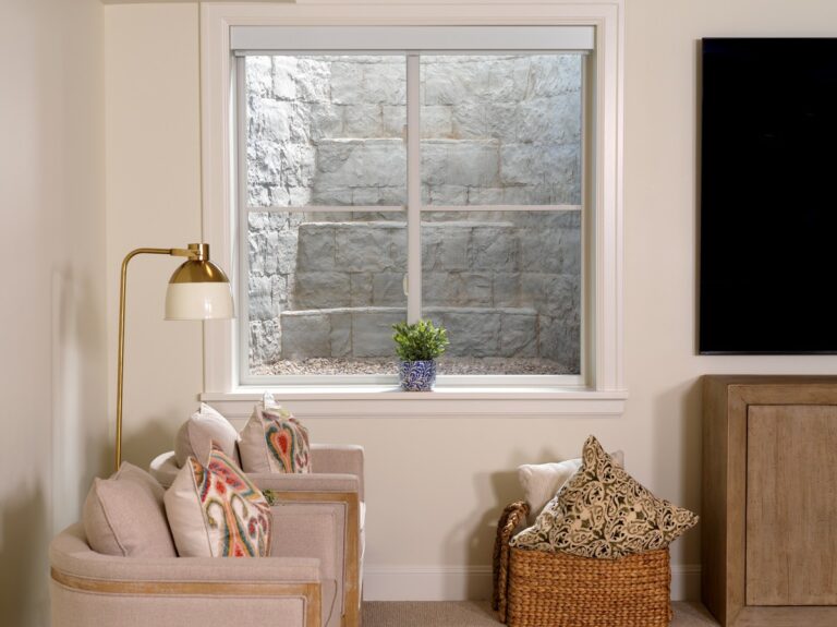 Basement room window framed by a stone-look window well