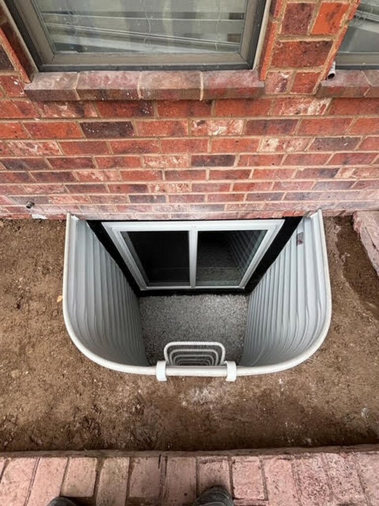 Galvanized steel window well with an escape ladder beside a brick home