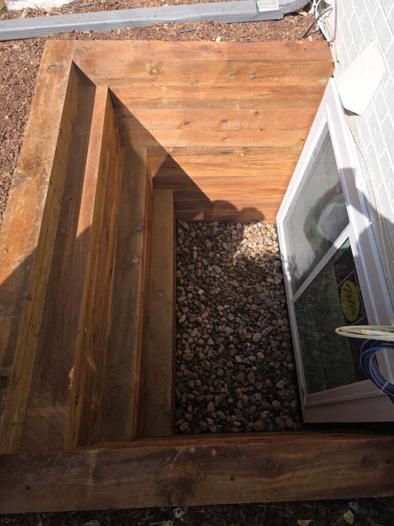 Timber window well steps beside a basement window